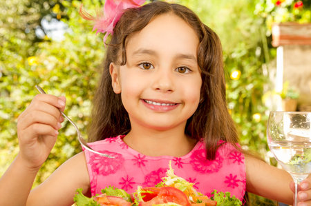Close up of beautiful girl, preparing to eat a healthy salad and drink a glass of water, in a garden backgroundの写真素材