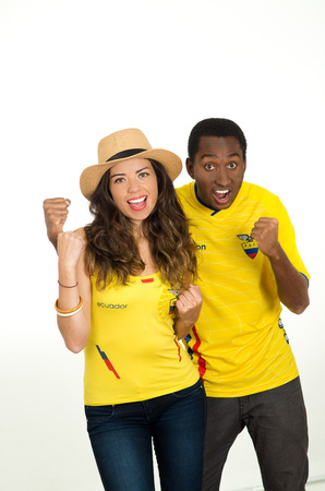 QUITO, ECUADOR - MAY 06, 2017: Close up of a young ecuadorian couple wearing official Marathon football shirt standing facing camera, very engaged body language watching game with great enthusiasm in white backgroundのeditorial素材