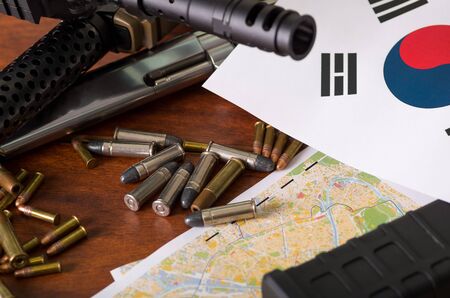 Close up of a shotgun and a revolver, cartridge belt with bullets with North Korean flag on a map, on wooden tableの写真素材