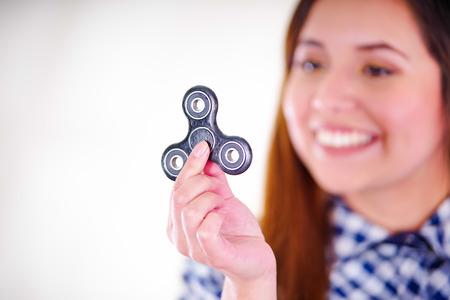 Close up of a beautiful woman holding a popular fidget spinner toy in her hand in white backgroundの写真素材