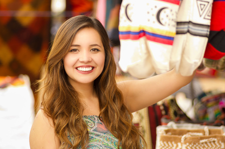 Close up of a beautiful woman holding an andean traditional handbag clothing textile yarn and woven by hand in wool, colorful fabrics backgroundの写真素材