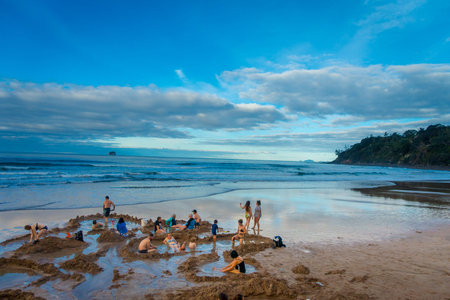 NORTH ISLAND, NEW ZEALAND- MAY 16, 2017: Tourists digging their own hot springs in Hot Water Beach, Coromandel. 130,000 annual visitors make it one of most popular attractions in Waikato region, in New Zealandのeditorial素材