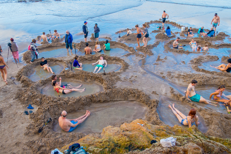 NORTH ISLAND, NEW ZEALAND- MAY 16, 2017: Visitors making small hot water pools in Hot Water beach.it one of the most popular geothermal attractions in New Zealand, about 700,000 people visit the beach annually.のeditorial素材