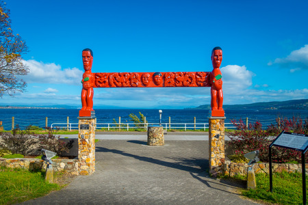 NORTH ISLAND, NEW ZEALAND- MAY 18, 2017: Beautiful red sculpture donated by Lucy Reid, view of wharf, and lovely view of Lake Taupo with mountains an city in the background at spring, North Island of New Zealand with beautiful blue skyのeditorial素材