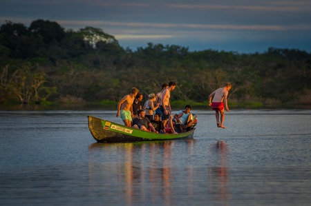 CUYABENO, ECUADOR - NOVEMBER 16, 2016: Young Tourists Jumping Into The Lagoon Grande Against The Sunset, Cuyabeno Wildlife Reserve, South Americaのeditorial素材