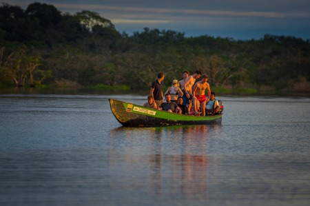 CUYABENO, ECUADOR - NOVEMBER 16, 2016: Young Tourists Jumping Into The Lagoon Grande Against The Sunset, Cuyabeno Wildlife Reserve, South Americaのeditorial素材