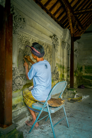BALI, INDONESIA - MARCH 08, 2017: Man using a chisel to do art on a wall of cement, in Denpasar Bali located in Indonesiaのeditorial素材