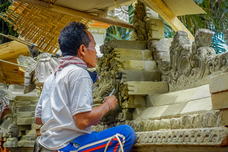 BALI, INDONESIA - APRIL 05, 2017: Man using a chisel to do art of cement, in Ubud Bali located in Indonesiaのeditorial素材