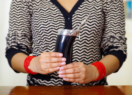 Woman holding traditional mate cup with typical metal straw sticking up, south american herbal recreation drinkの写真素材