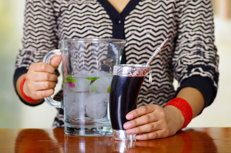 Woman holding traditional mate cup with typical metal straw sticking up, south american herbal recreation drinkの写真素材