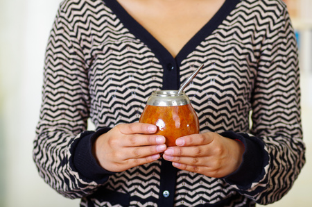 Woman holding traditional mate cup with typical metal straw sticking up, south american herbal recreation drinkの写真素材