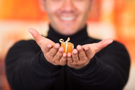 QUITO, ECUADOR- 17 OCTOBER, 2015: Close up of a young man holding in his hands a golden gift present.のeditorial素材