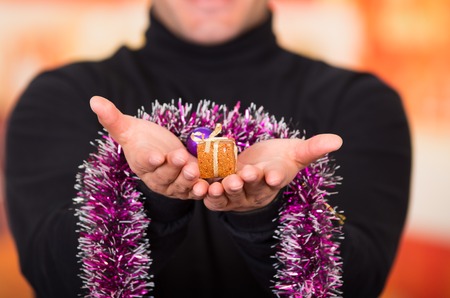 QUITO, ECUADOR- 17 OCTOBER, 2015: Close up of a young man holding in his hands a gift and a colorful christmas tree decorationのeditorial素材