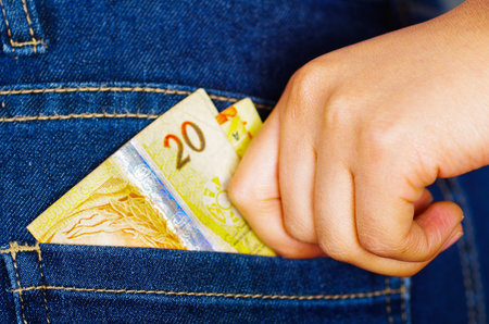 Woman hand putting money bill inside of jeans back pocketの写真素材