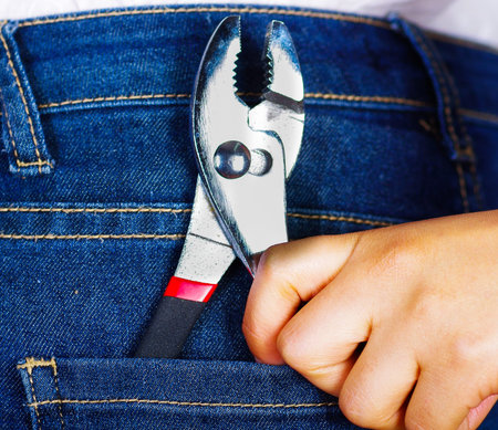 Woman hand holding a plier inside of jeans back pocketの写真素材