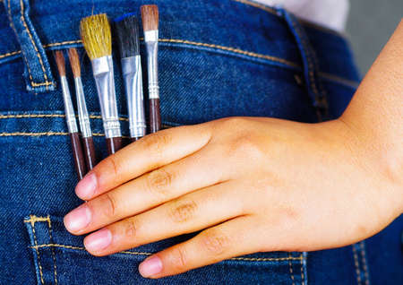 Woman hand holding a small paintbrush inside of jeans back pocketの写真素材