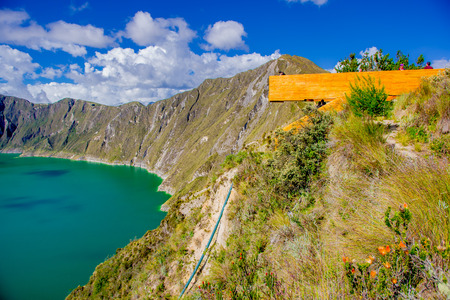QUITO, ECUADOR - NOVEMBER, 25 2016: Unidentified people enjoying the view of lake with a beautiful magenta color of the Quilotoa caldera from a wooden structure lookout. Quilotoa is the western volcano in Andes range and is located in andean region of Ecuのeditorial素材
