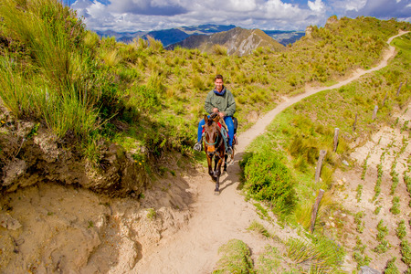 QUITO, ECUADOR - NOVEMBER, 25 2016: Unidentified young tourist riding a horse trought a sandy path near Quilotoa inactive volcano. Quilotoa is the western volcano in Andes range and is located in andean region of Ecuadorのeditorial素材