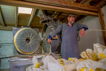 QUITO, ECUADOR - NOVEMBER 23, 2016: Unidentified man working in an old stone grinder mill made to...