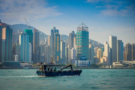 HONG KONG, CHINA - JANUARY 26, 2017: Fisher in his boat with a beautiful view ofHong Kong in the horizont, with a skyscrapers and modern buildings.のeditorial素材