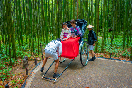 KYOTO, JAPAN - JULY 05, 2017: Unidentified people over a red rickshaw in a path at beatiful bamboo forest at Arashiyama, Kyoto, Japanのeditorial素材