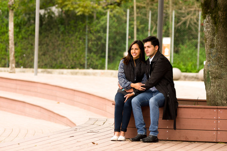 Beautiful young couple in love in st valentines day sitting in a parkの写真素材