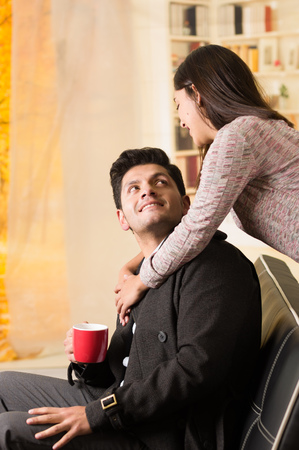 Beautiful young couple in love in st valentines day, man holding a red cup in a blurred office backgroundの写真素材