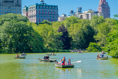 NEW YORK, USA - NOVEMBER 22, 2016: Unidentified group of people paddling in the Lake in Central Park in a beautiful sunny day, with a huge buildings behind in New Yorkのeditorial素材
