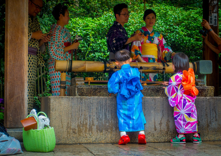 KYOTO, JAPAN - JULY 05, 2017: Young Japanese people wearing traditional Kimono and holding umbrellas in their hands in the Gion district of Kyoto, Gion is Kyotos most famous geisha districtのeditorial素材