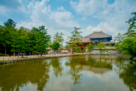 Nara, Japan - July 26, 2017: Unidentified people walking to Todai-ji temple with an Eastern Great Temple behind, and a beautiful artificial lake with tree reflections. This temple is a Buddhist temple located in the city of Naraのeditorial素材