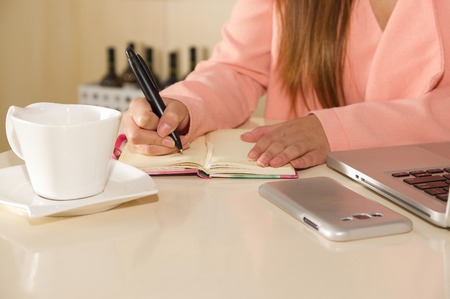 Close up of businesswoman hand working and holding with one hand a pen and writting on an agenda the activity schedule. Business conceptの写真素材