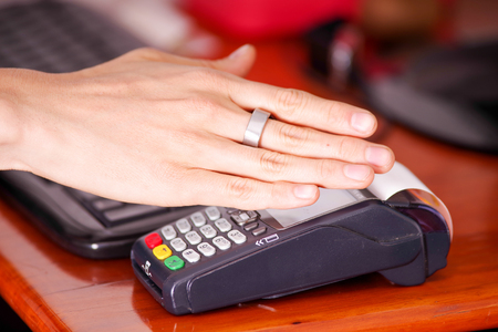Modern payment with new technology of payments using a smart ring, buy and sell products service on a wooden tableの写真素材