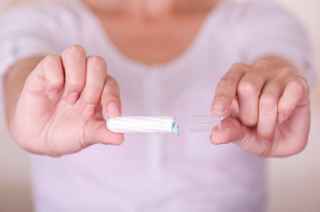 Close up of a young woman pointing in front of her a menstruation cotton tampon in a blurred...