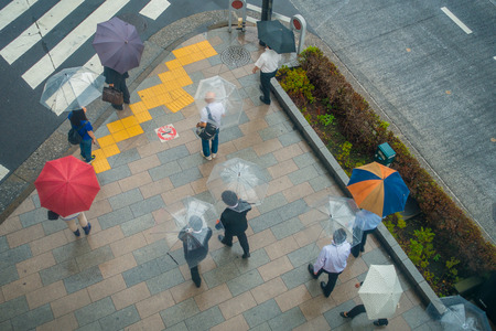 TOKYO, JAPAN JUNE 28 - 2017: Aerial view of unidentified people under umbrellas on zebra crossing street in Jimbocho district located in Tokyoのeditorial素材