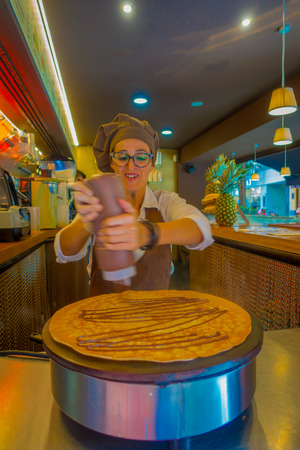 PALMA DE MALLORCA, SPAIN - AUGUST 18 2017: Close up of unidentified woman, preparing a crepe on an electric cooker, adding some caramelのeditorial素材