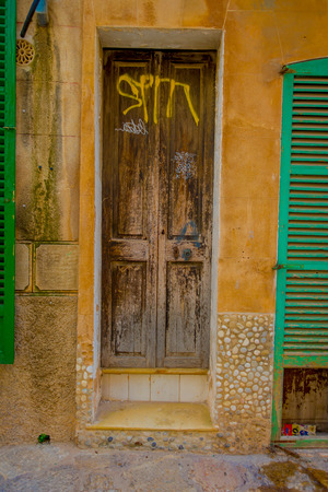 PORT D ANDRATX, SPAIN - AUGUST 18 2017: Beautiful view of small old brown door in a damaged wall, in Port D Andratx town, located in Mallorca balearic islands, Spainのeditorial素材