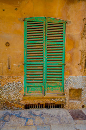 PORT D ANDRATX, SPAIN - AUGUST 18 2017: Beautiful view of small old green door in a damaged wall, in Port D Andratx town, located in Mallorca balearic islands, Spainのeditorial素材