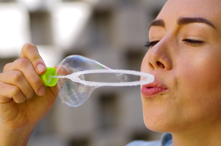 Woman playing with soap bubbles on a summer nature, in a blurred nature background