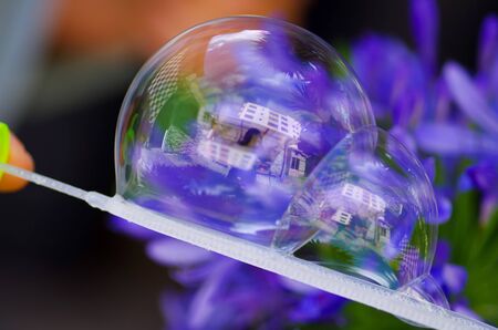 Close up of a soap buble on a blurred purple background, with a building reflection in the bubleの写真素材