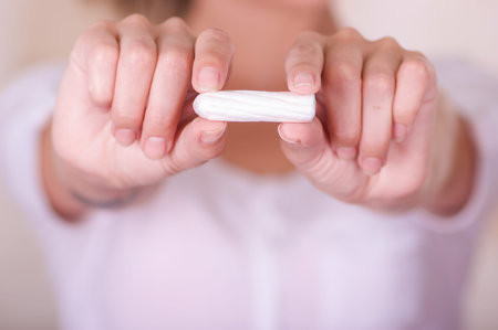 Close up of a young woman pointing in front of her a menstruation cotton tampon in a blurred...