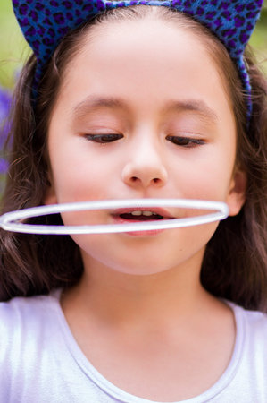 Portrait of happy little gril playing with soap bubbles on a summer natureの写真素材