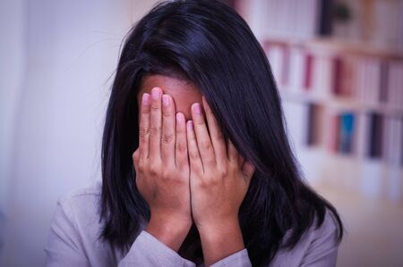 Portrait of a depressed teenager sitting holding head in hands, stressed sad young woman having mental problems, feeling bad, need psychological help, addicted heartbroken girl experiencing adolescence crisisの写真素材