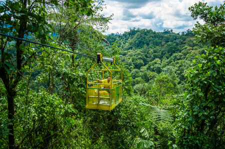 MINDO, ECUADOR - AUGUST 27, 2017: Unidentified man with a dog inside of the Tarabita crossing deep valley, up to 152 m above the ground located in Mindo, Ecuadorのeditorial素材
