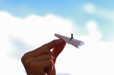 Miniature little people, man inside of a paper airplane in a sky background