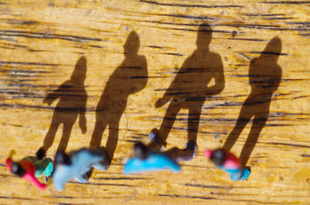Miniature little people, friend at outdoors with shadow in the floor, in a wooden background, top...