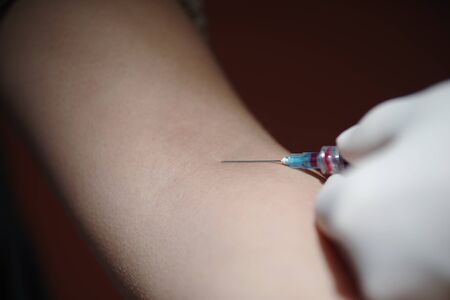 Close up of a needle injection treatment in her armの写真素材