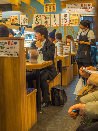 TOKYO, JAPAN -28 JUN 2017: Unidentified people eating an assorted japanesse food over a table, inside of a kaitenzushi conveyor belt sushi restaurant, in Tokyoのeditorial素材