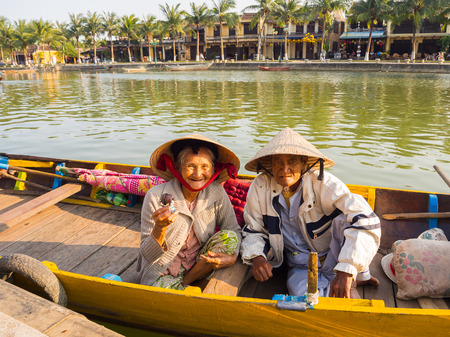 HOIAN, VIETNAM, SEPTEMBER, 04 2017: Unidentified old couple in the traditional boats in front of ancient architecture in Hoi An, Vietnam.のeditorial素材