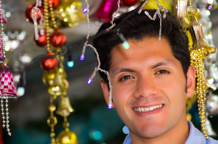 QUITO, ECUADOR- 07 MAY, 2017: Close up of a handsome young man watching beautiful and colorful christmas tree decoration in a market.のeditorial素材