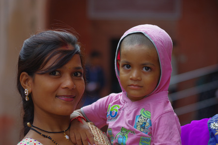 Agra, India - September 20, 2017: Portrait of a beautiful teenager holding her little sister in their arms, looking at camera in Agra city in Indiaのeditorial素材